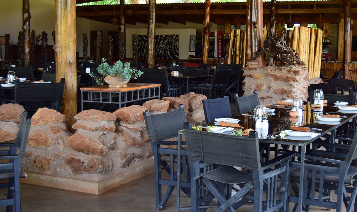 An outdoor dining area with stone walls, wooden tables, and chairs.