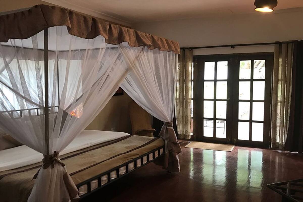 A room with a bed, a chair, a window, and a door.