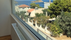 Un balcon offrant une vue sur une ville côtière, avec ses bâtiments et une île située au loin.