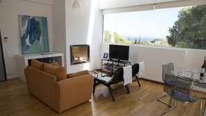 Un salon moderne comprenant un canapé, une table basse en verre, un téléviseur et un coin repas avec une table et des chaises en verre.