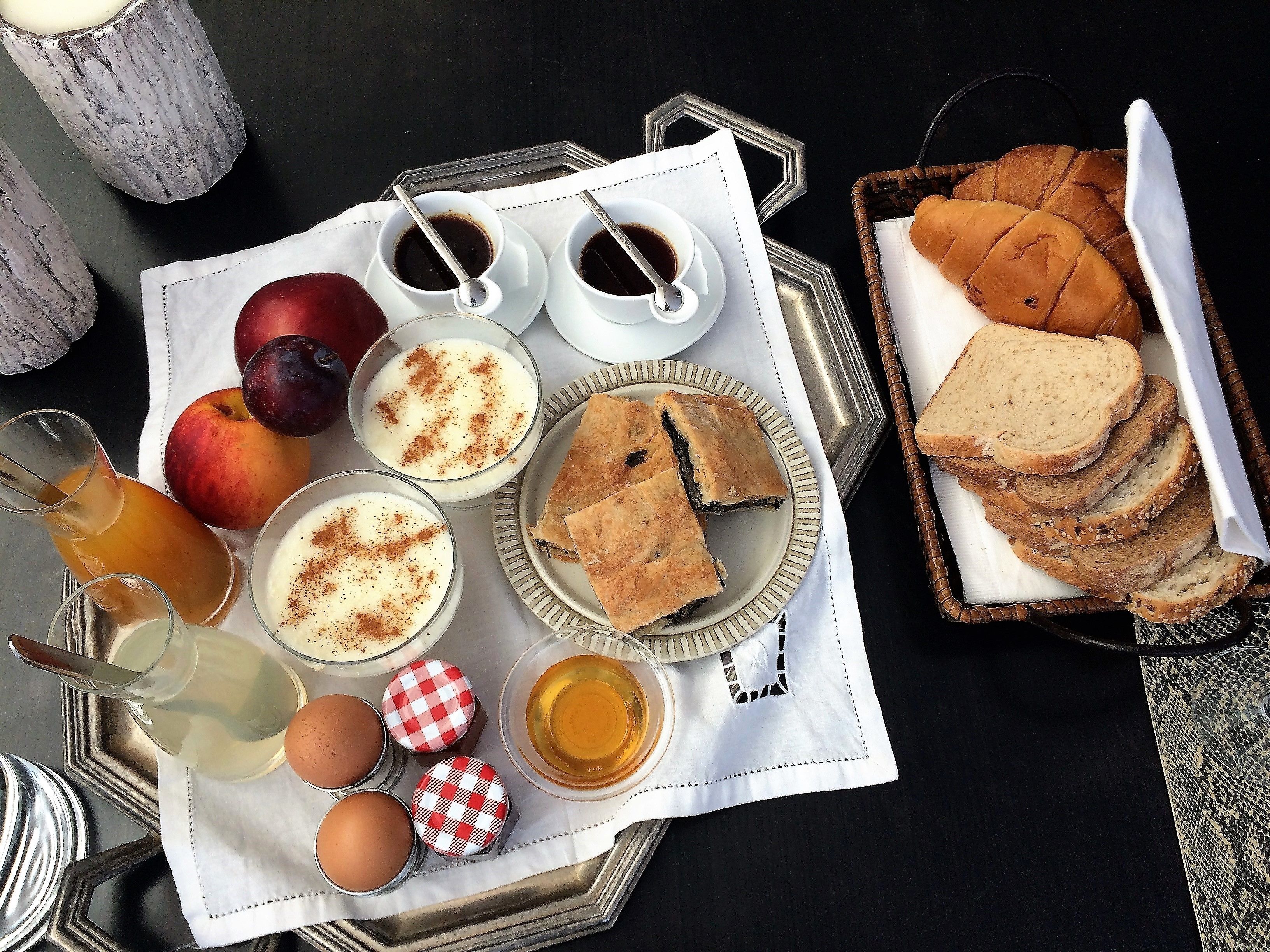 Bandeja de desayuno con diversos alimentos y bebidas, incluyendo pan, pastelería y fruta.