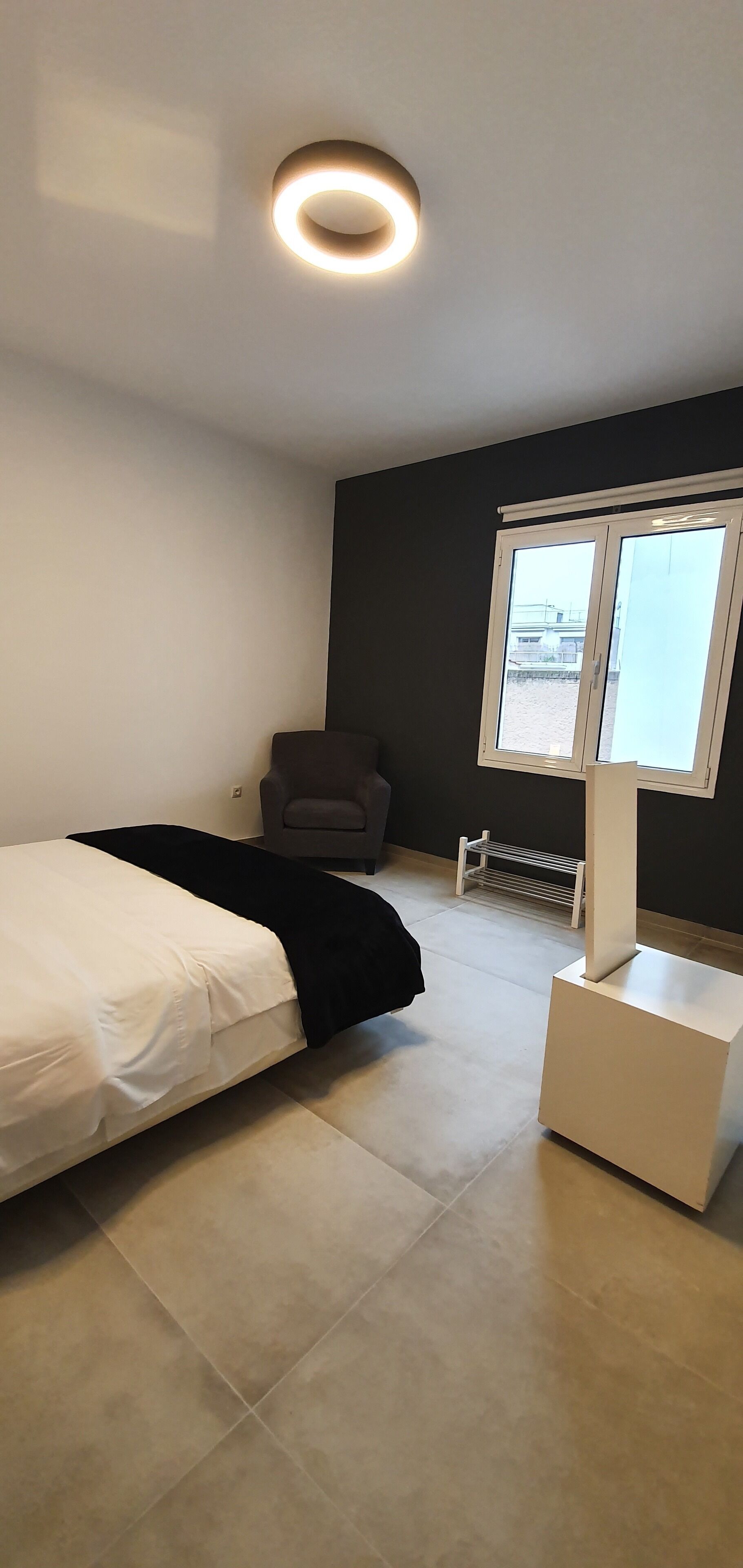 A modern bedroom with a bed, a chair, a radiator, and a window.