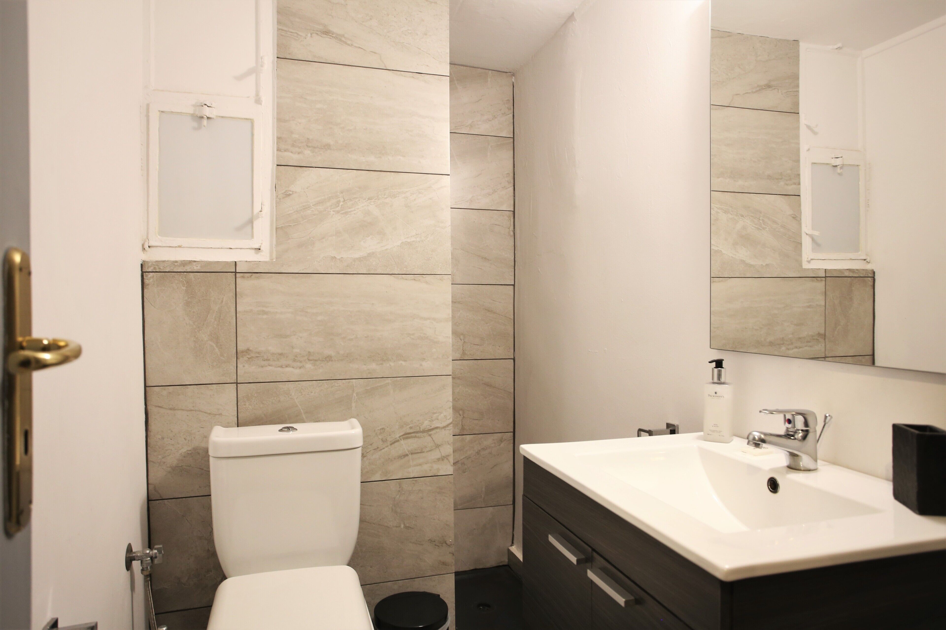 A modern bathroom with a toilet, sink, and mirror.