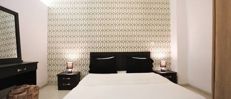 A bedroom with a bed, bedside tables, a mirror, and a patterned wall.