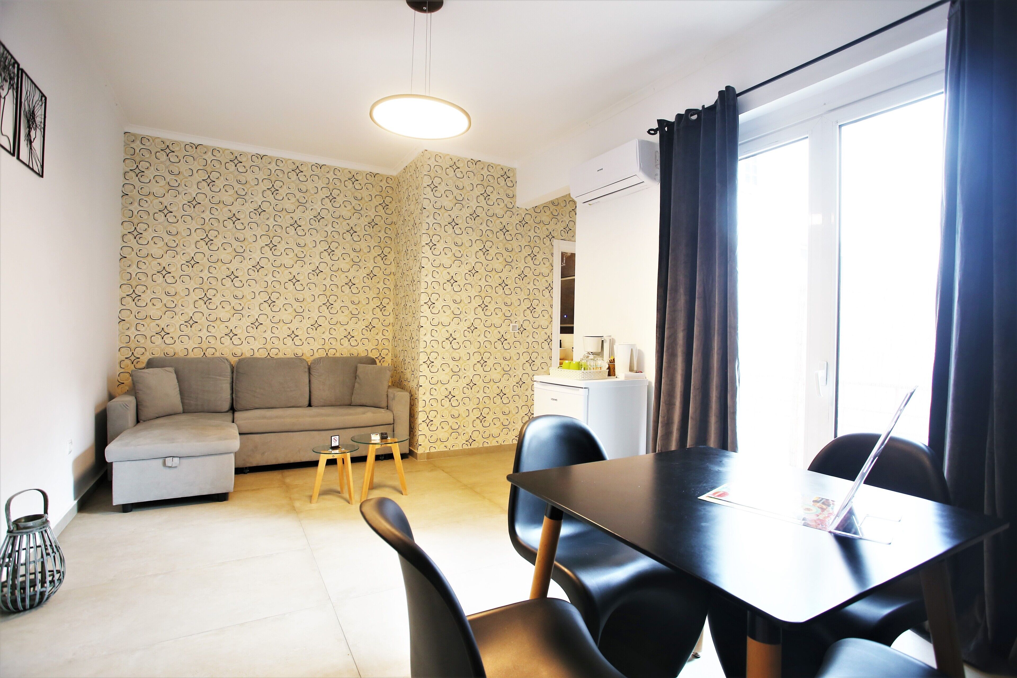 Un espace de vie compact comprenant un canapé, une table à manger, des chaises et un coin cuisine.