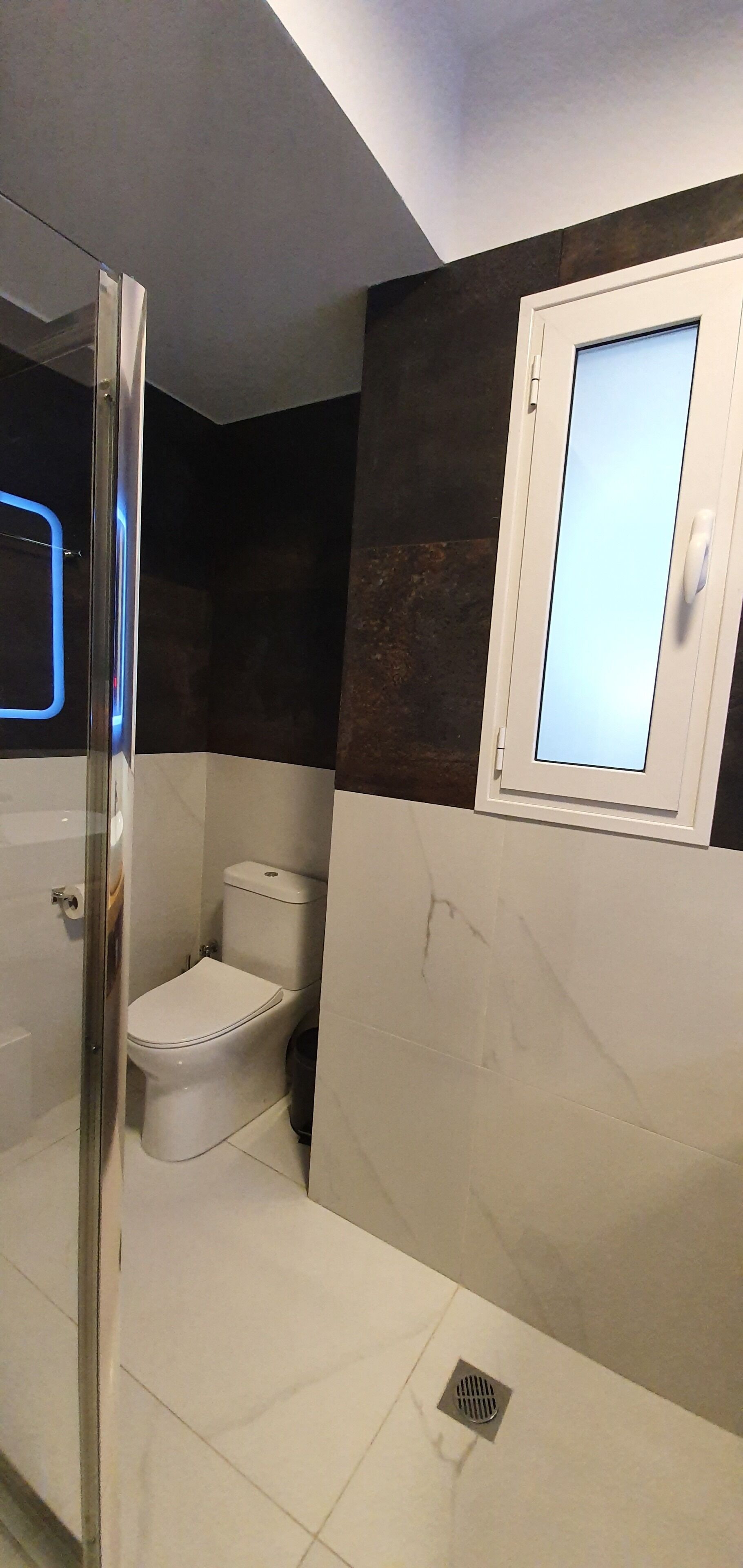 Un baño con inodoro, ducha y ventana.