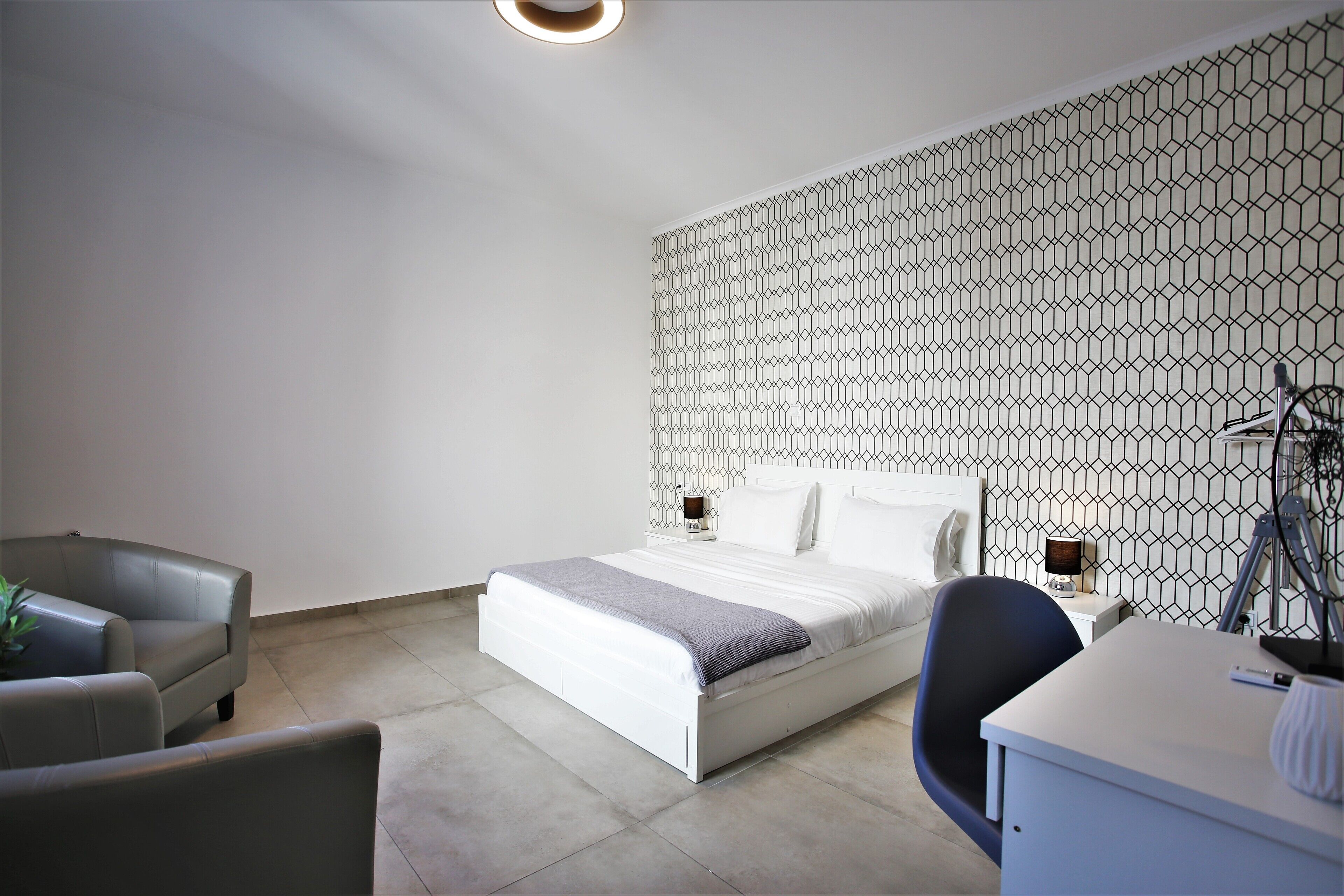 Un dormitorio moderno con cama, escritorio y silla.