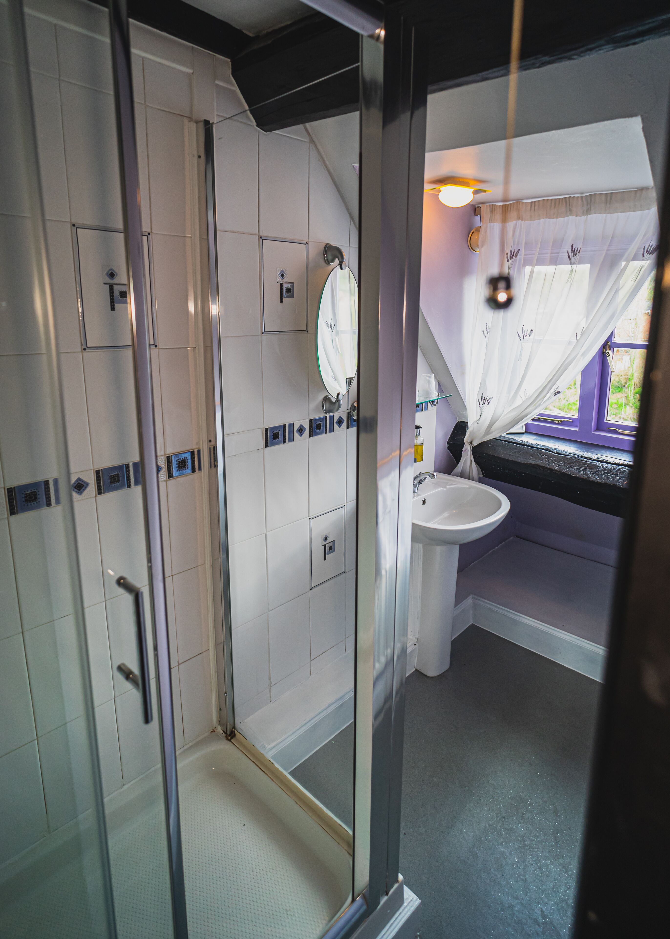 A bathroom with a glass shower enclosure, a white sink, and a mirror.
