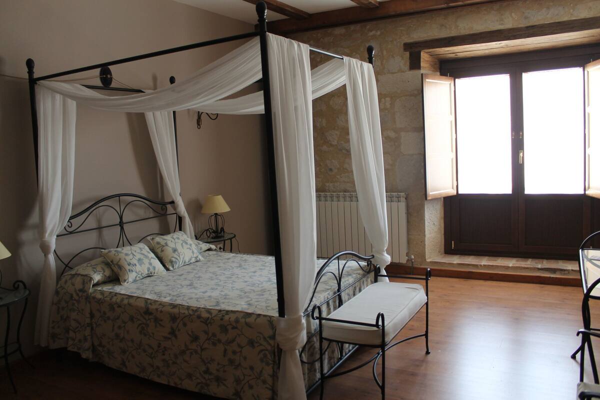 Un lit à baldaquin, une table de chevet avec une lampe et un banc.