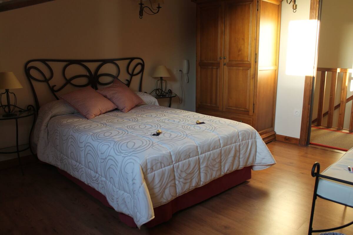 Une chambre à coucher avec un lit, une armoire en bois et une table de chevet avec une lampe.