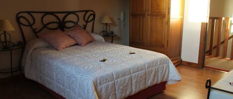 Un dormitorio con cama, armario de madera y mesita de noche con lámpara.