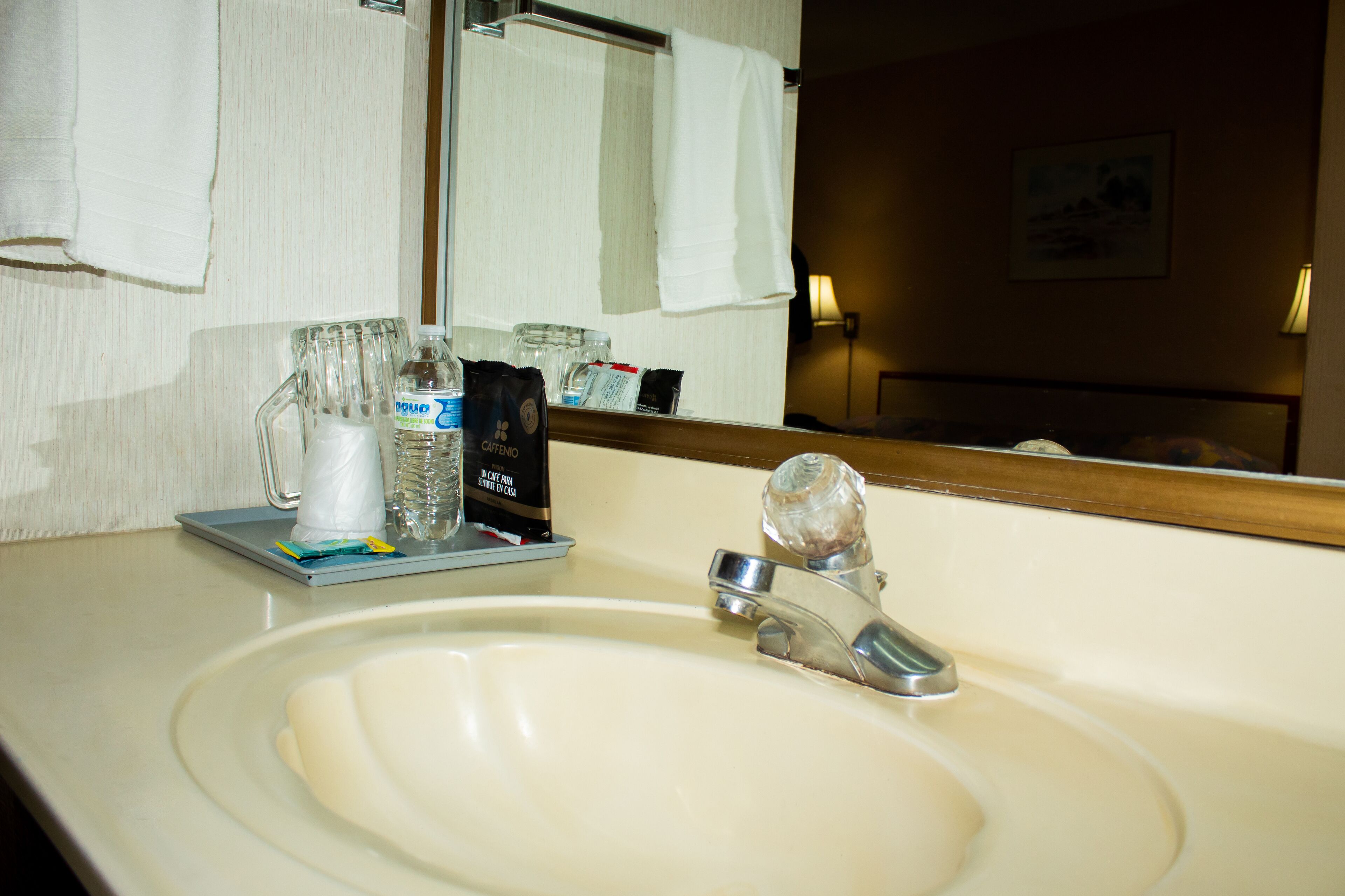 Un baño de hotel con lavamanos, espejo y artículos de aseo.