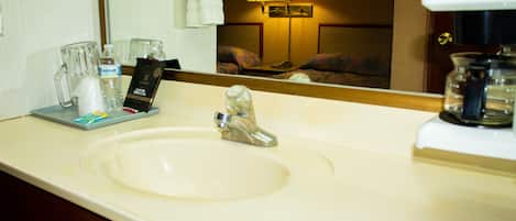 Un baño de hotel con lavamanos, espejo y cafetera.