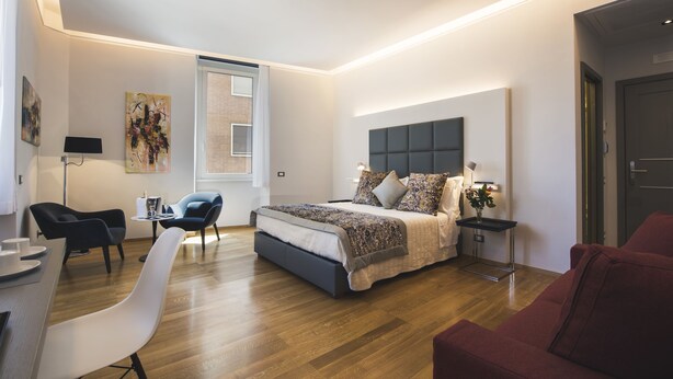 A modern bedroom with a large bed, a desk, and a chair. - Mascherino Suites (Rome)