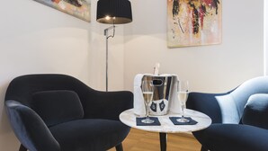 A modern room with two dark blue armchairs, a small round table with a white marble top, and a floor lamp. - Mascherino Suites (Rome)