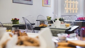 A breakfast setting with a croissant, coffee, and flowers on the table. - Mascherino Suites (Rome)
