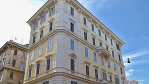 A multi-story building with classical architecture, featuring a corner entrance, multiple windows, and a balcony on the second floor. - Mascherino Suites (Rome)