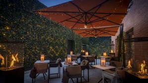 An outdoor patio with tables and chairs, surrounded by a brick wall and a leafy hedge. - Hotel 7 Dublin (Dublin)