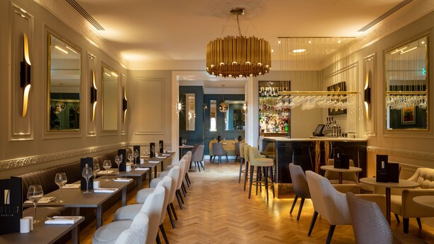 A hotel bar with a long counter, multiple seating areas, and a bar stocked with bottles. - Hotel 7 Dublin (Dublin)