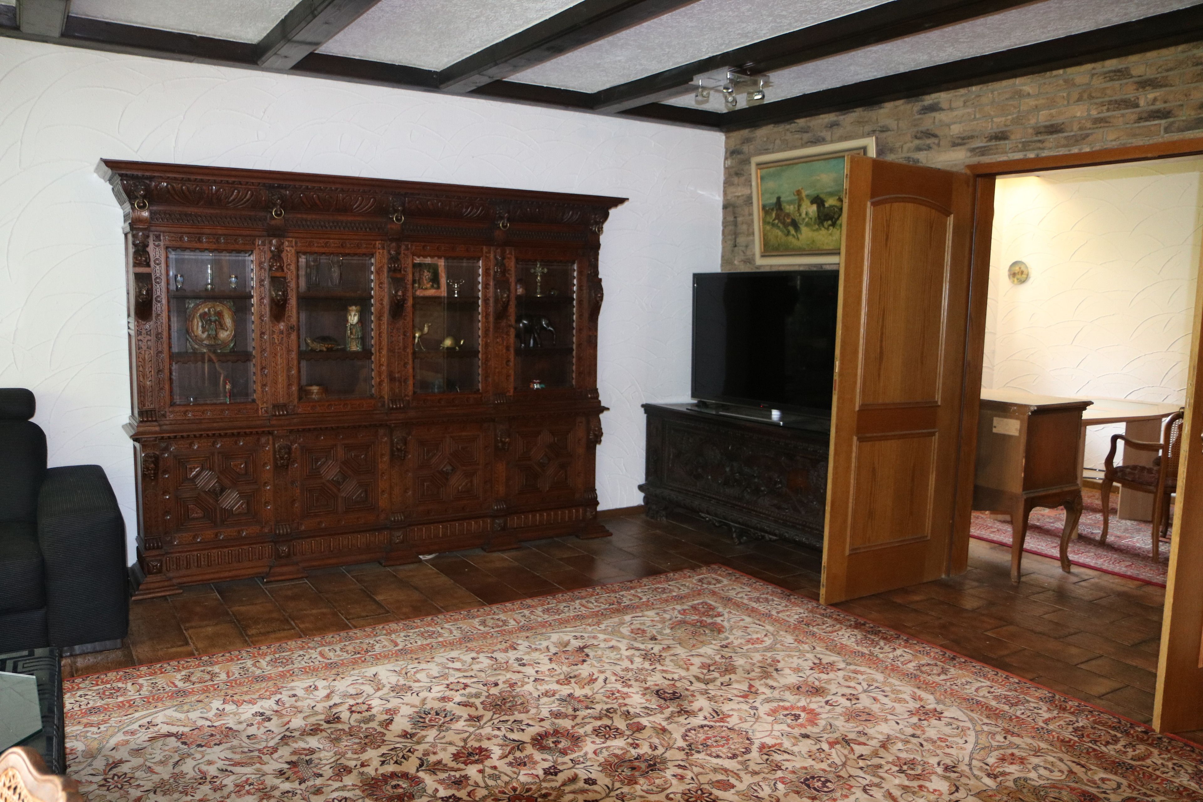Una habitación con un armario de madera grande, televisión y una alfombra estampada.