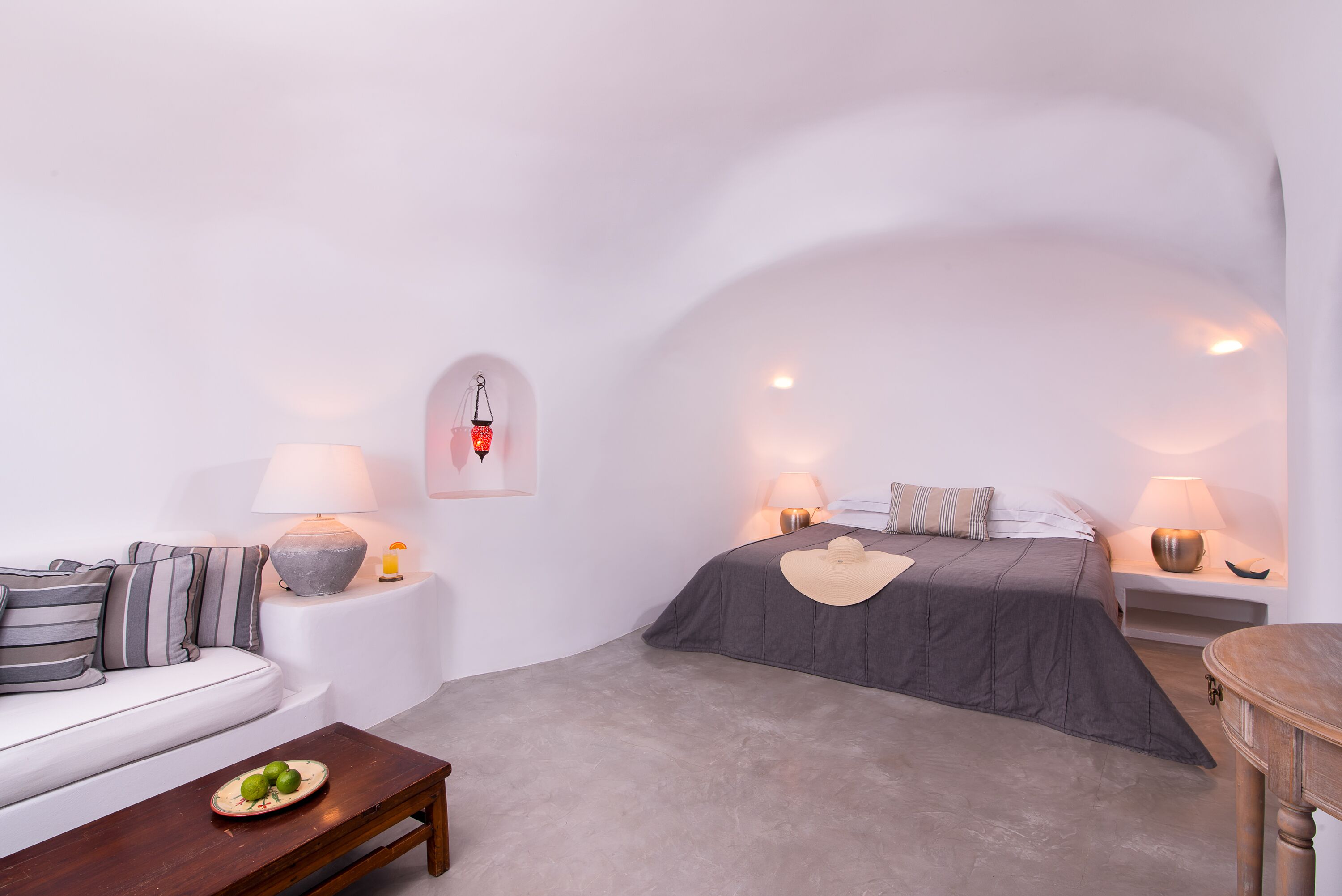 A minimalist bedroom with a bed, bedside tables, a sofa, and a coffee table.