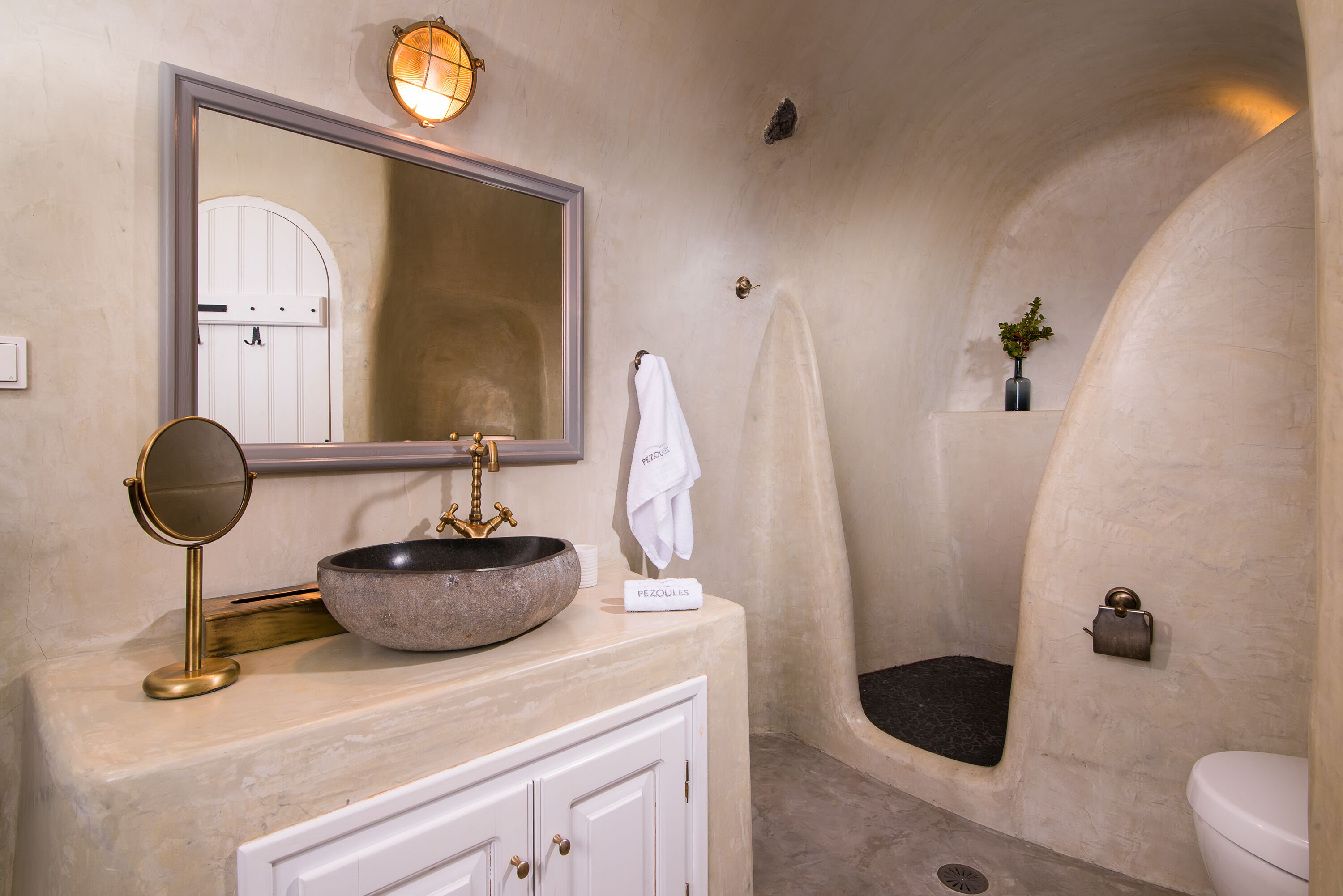 A bathroom with a round sink, a mirror, a towel rack, and a shower.