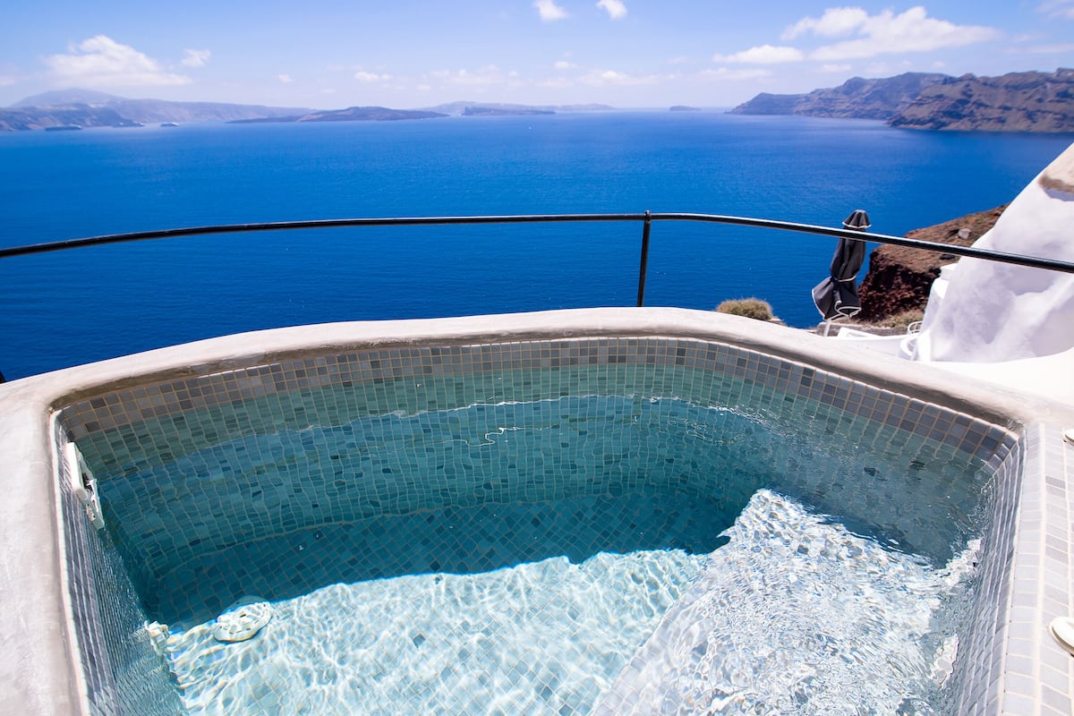 A hot tub with a clear view of the sea and distant mountains.