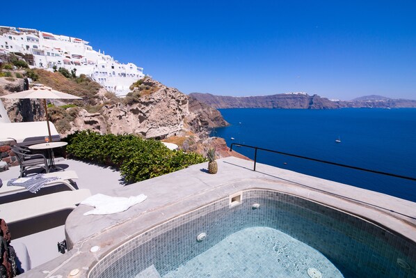 A pool area with a view of the sea and white buildings in the background. - Pezoules of Oia (Santorini)