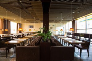 A spacious restaurant with high ceilings, wooden paneling, and large windows. Tables and chairs are arranged for dining. - Stop Hotel (Sînpetru)