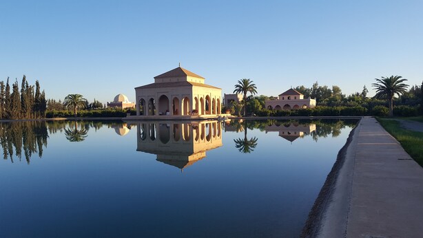 Un edificio grande con una cúpula y ventanas arqueadas, reflejado en una superficie de agua tranquila.