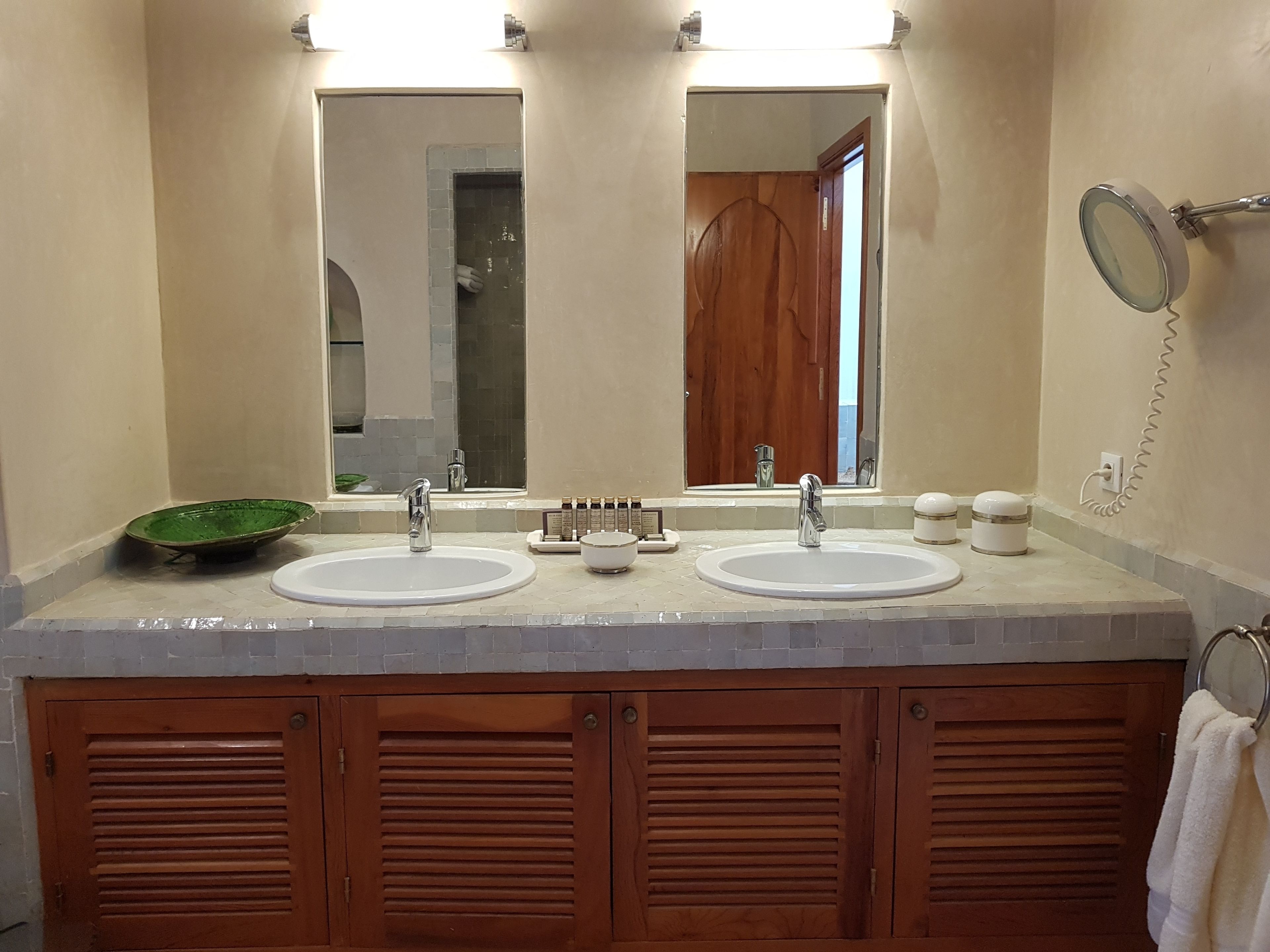Un baño con dos lavamanos, un espejo y un cuenco verde.