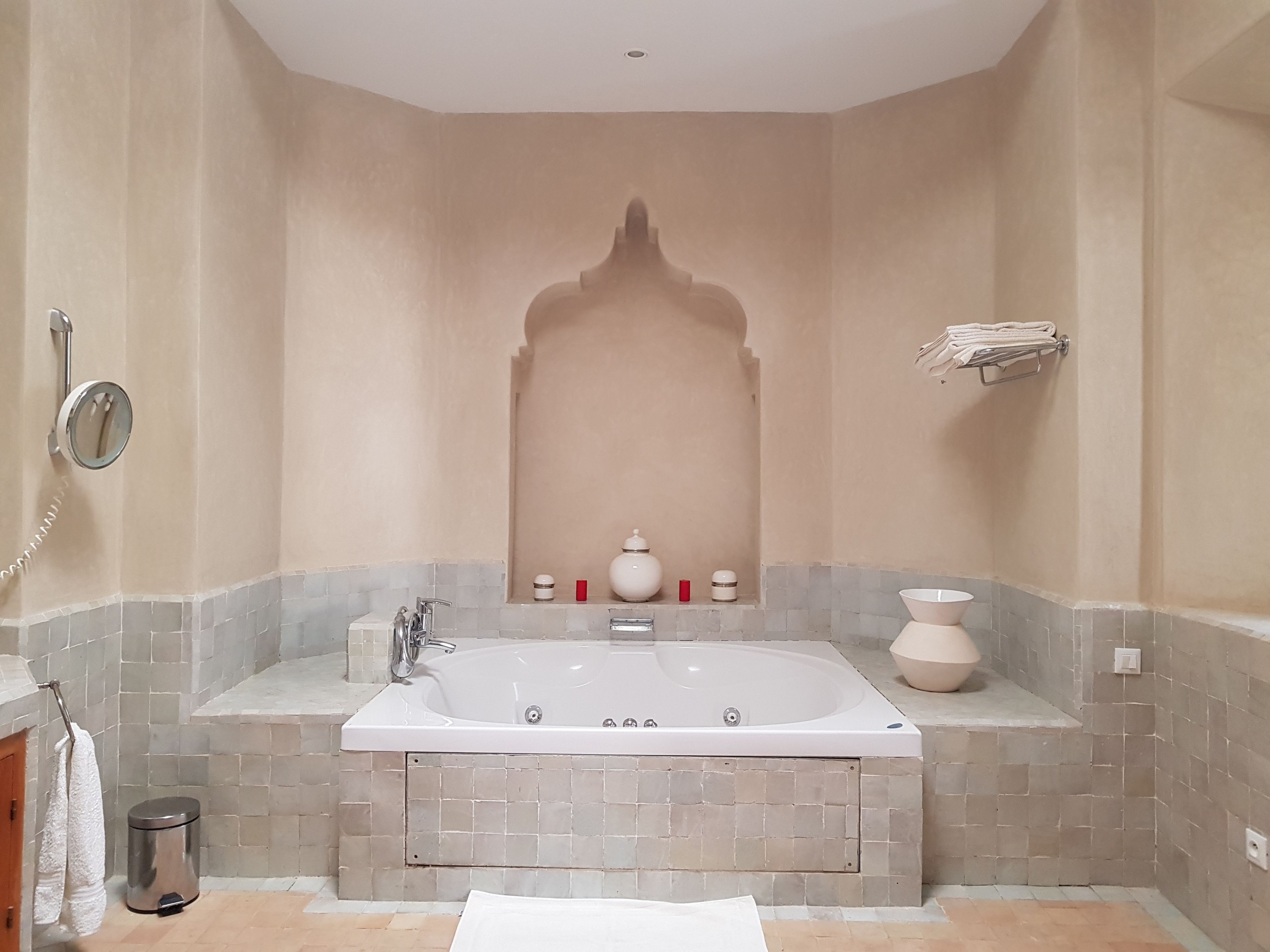 Un baño con una bañera grande, un espejo y un perchero para toallas.