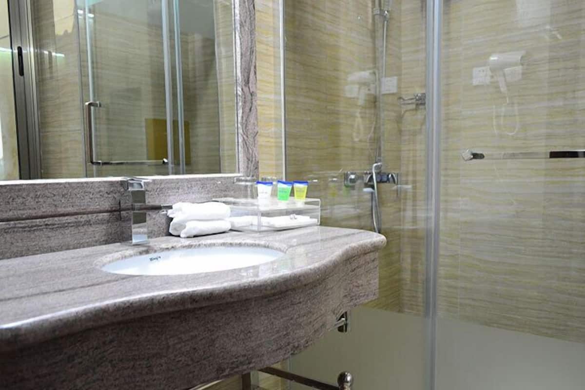 A bathroom with a granite countertop, a sink, and a glass shower enclosure.
