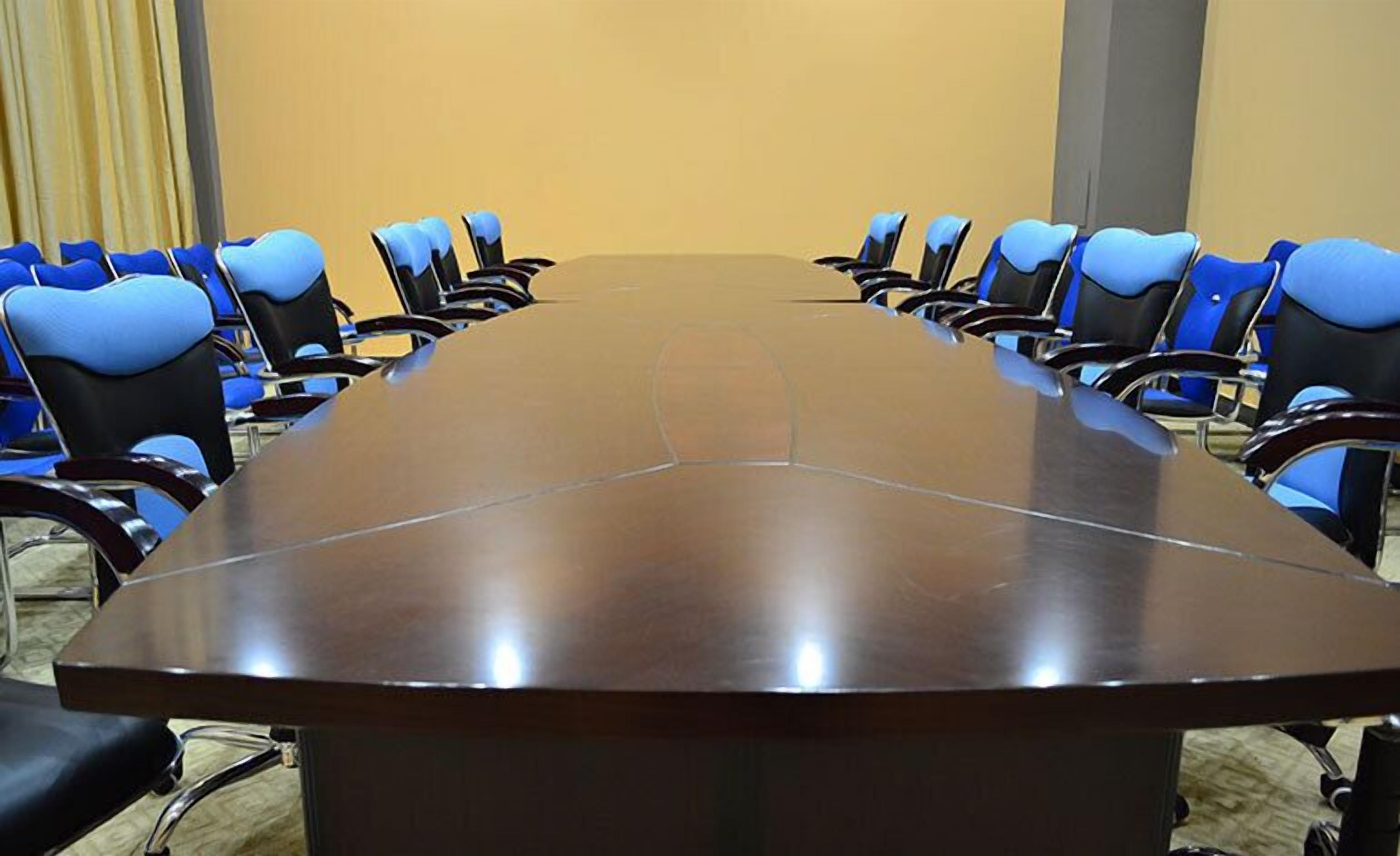 A conference room with a long table and blue chairs.