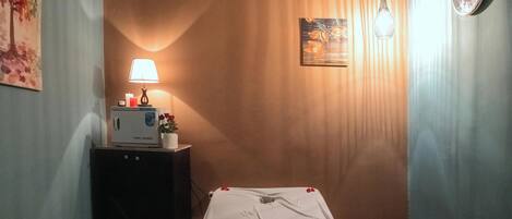 A hotel room with a bed, a nightstand with a lamp, a towel warmer, and a painting on the wall.