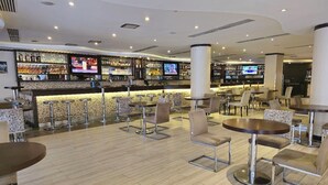A modern bar area with multiple seating options, including round tables and bar stools, and a well-stocked bar counter. - Best Western Plus Addis Ababa (Addis Ababa)