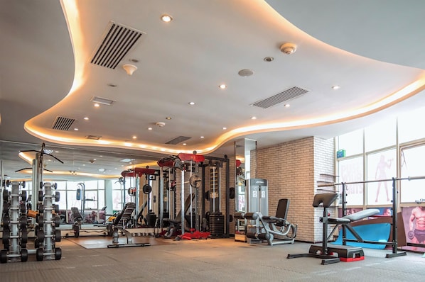 Un gimnasio moderno con diverso equipamiento de ejercicio, diseño de techo curvo y ventanas amplias.