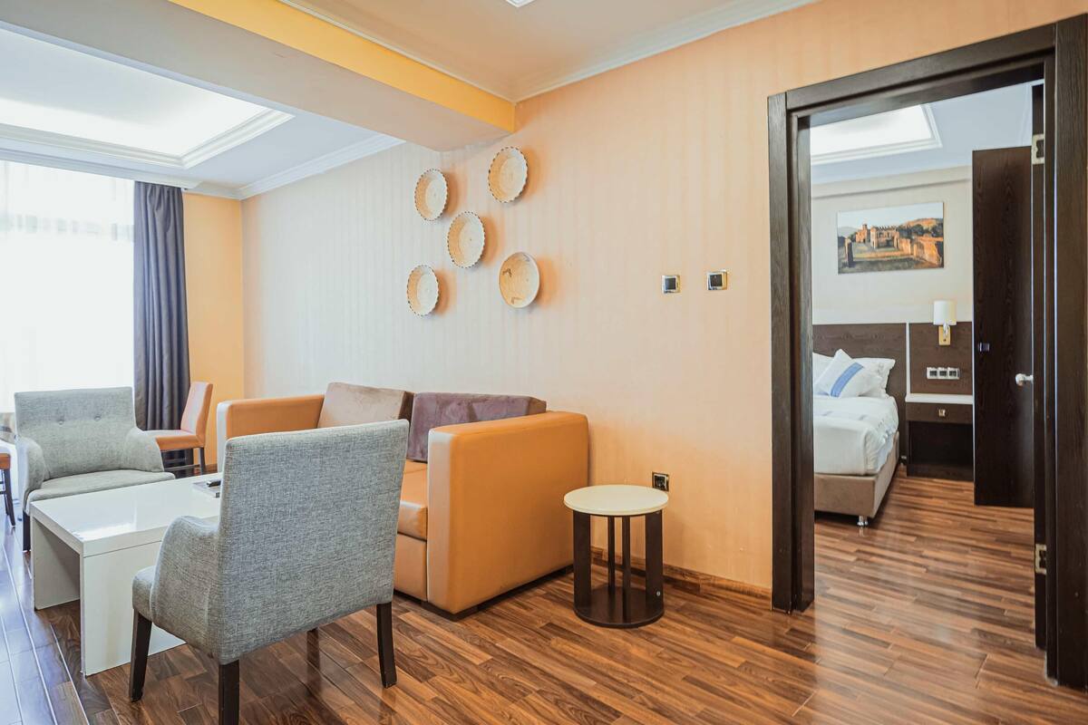 A hotel room with a sofa, chairs, a small table, and a bed.