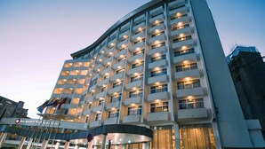 Een modern hotel met een gebogen gevel, meerdere balkons en een opvallende entree.