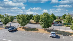 A parking lot with several cars, trees, and a clear sky. - B&B HOTEL Bourges (1) (Bourges)