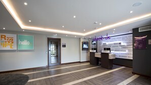 A hotel reception area with a modern design, featuring a reception desk, a digital information screen, and a wall with motivational quotes. - Premier Inn Abergavenny (Llanfoist)