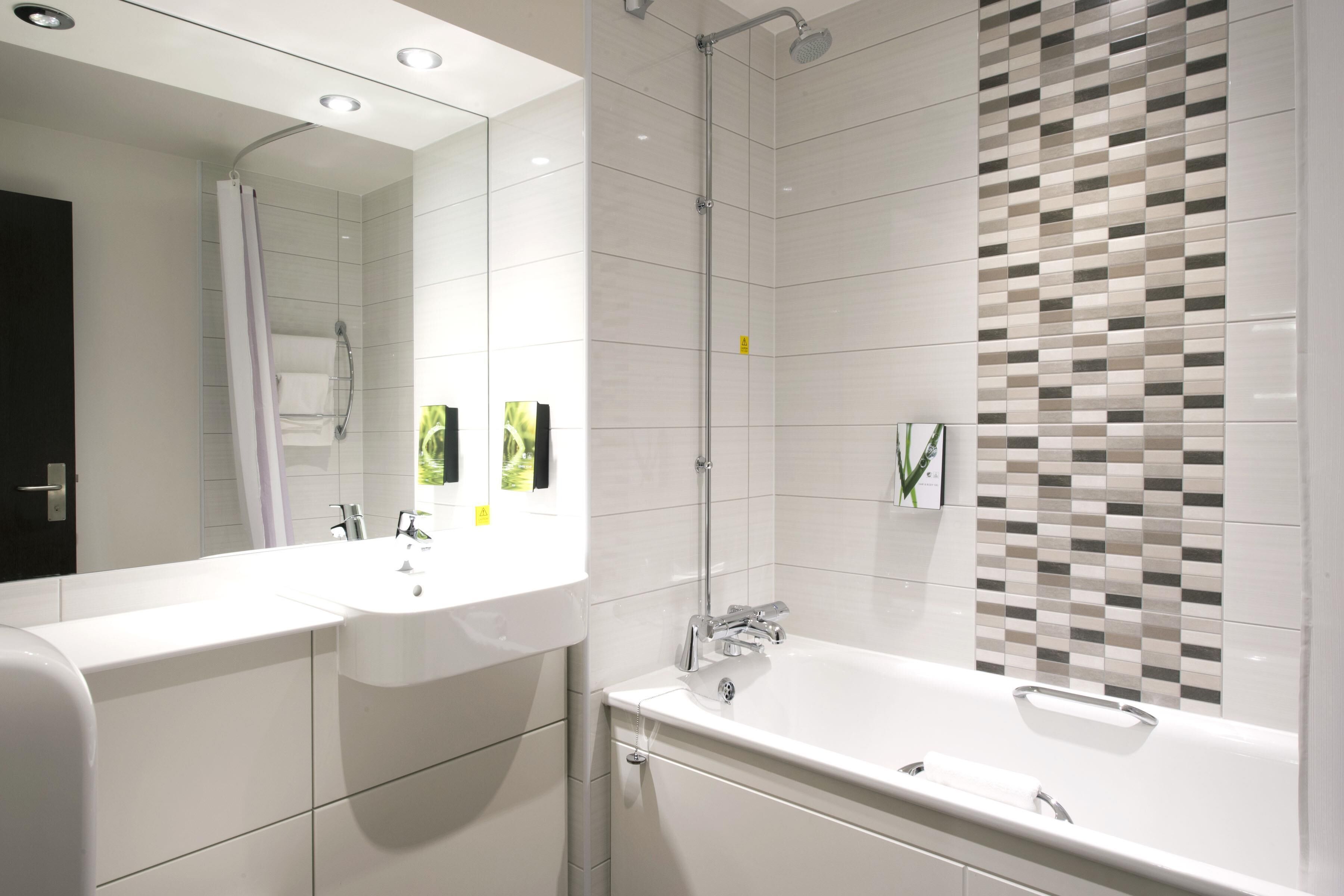 A modern bathroom with a double sink, a shower, and a large mirror.