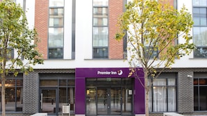 L’entrée d’un hôtel, avec un auvent violet, de grandes fenêtres et une façade en briques.