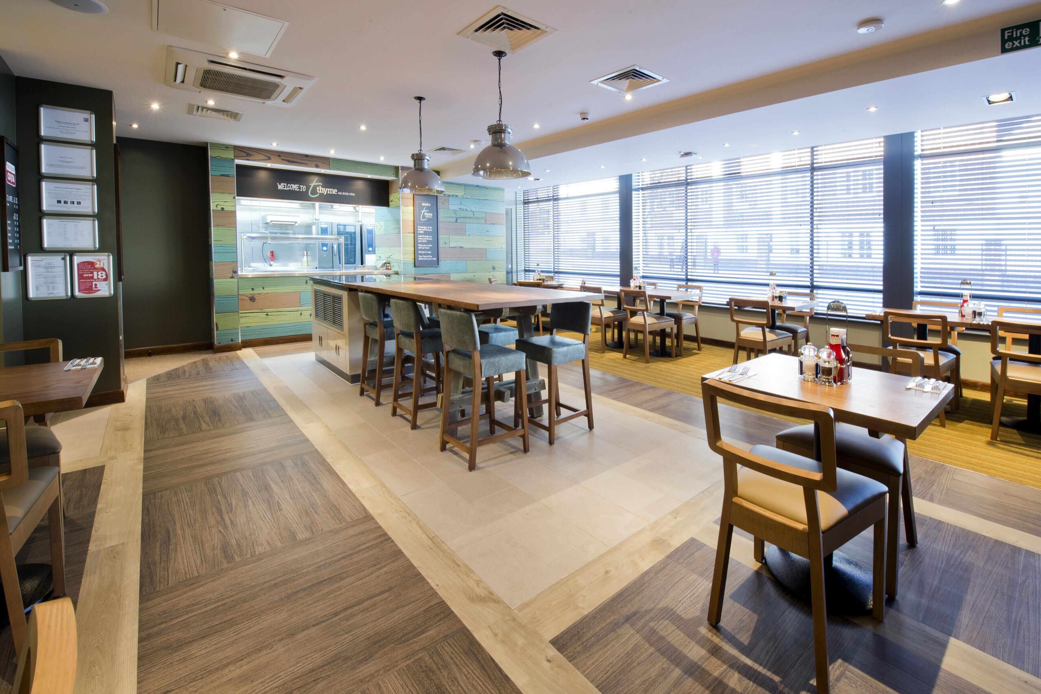 A modern restaurant with a bar area, multiple seating options, and large windows providing natural light.