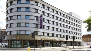 Un hotel a più piani con facciata curva, segnaletica con scritto 'Royal Arsenal Hotel' e uno striscione con 'Premier Inn'.