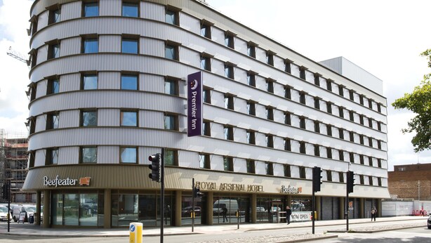 A multi-story hotel with a curved facade, signage for 'Royal Arsenal Hotel,' and a 'Premier Inn' banner.