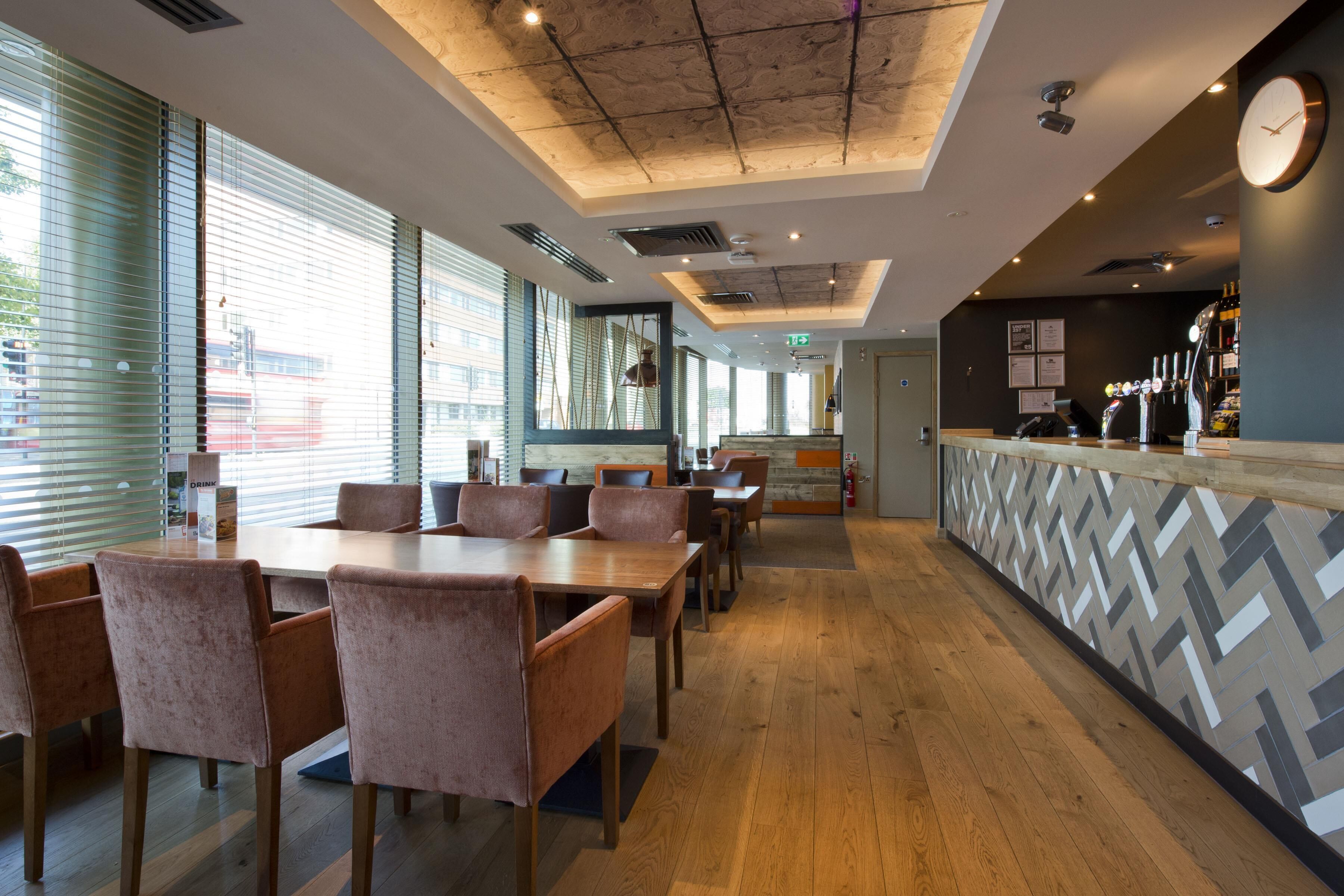 A restaurant with a long counter, multiple tables, and chairs.