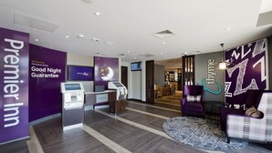 A hotel lobby with a reception desk, a check-in kiosk, and a seating area with purple chairs. - Premier Inn Milton Keynes Central - Theatre District (Milton Keynes)