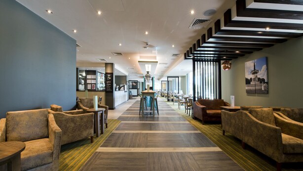 A hotel lobby with sofas, a central table, and a staircase. - Premier Inn Milton Keynes Central - Theatre District (Milton Keynes)