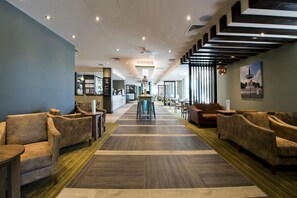 A hotel lobby with sofas, a central table, and a staircase. - Premier Inn Milton Keynes Central - Theatre District (Milton Keynes)